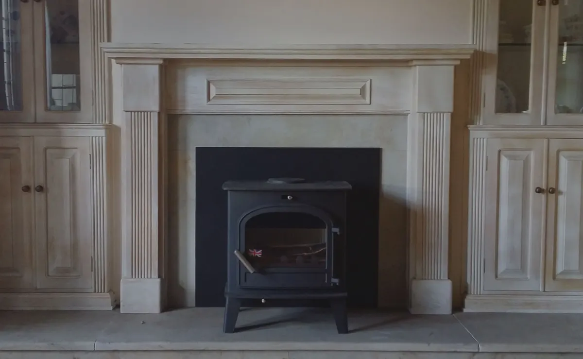 Restored black wood stove set into a painted timber mantelpiece