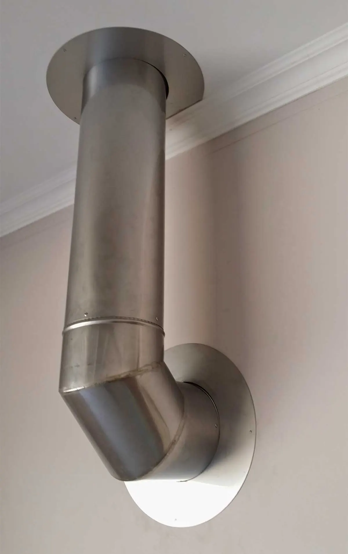 Stainless steel flue elbow passing neatly through an interior wall