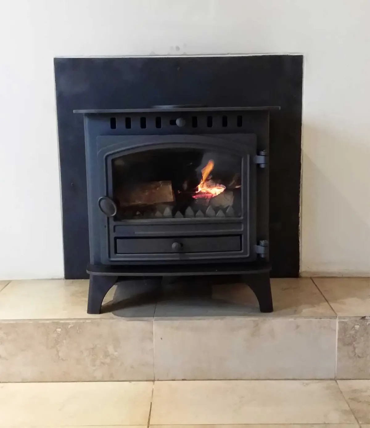 Built-in cast-iron insert alight on a sandstone hearth with a black steel surround