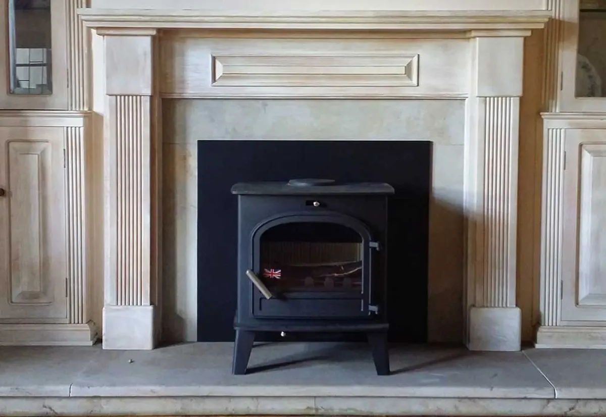 Black wood stove set into a limewashed timber mantel in a Cape cottage