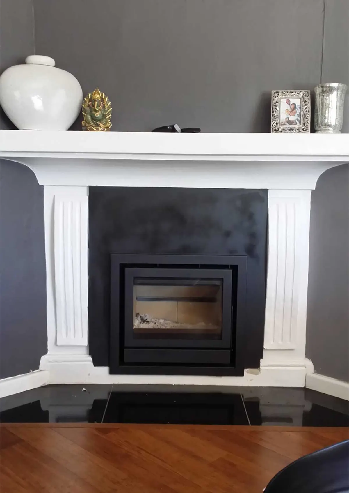 Closed-system insert fitted into a white painted mantelpiece against a charcoal wall