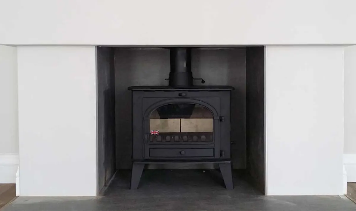 Black stove recessed into a clean white surround with a slate hearth